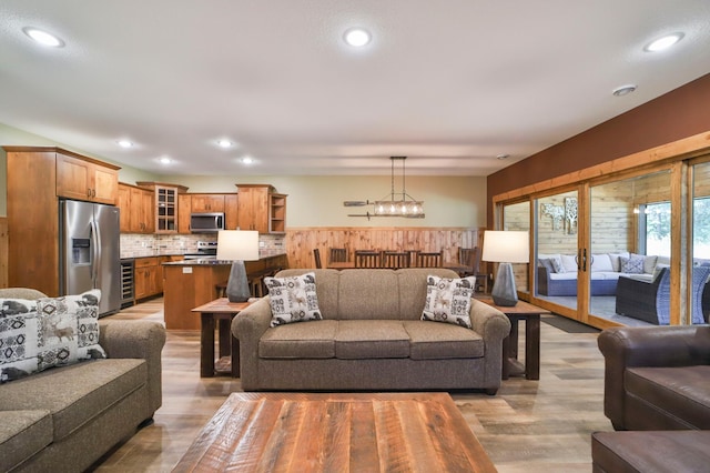 living room with an inviting chandelier, wine cooler, and light wood-type flooring