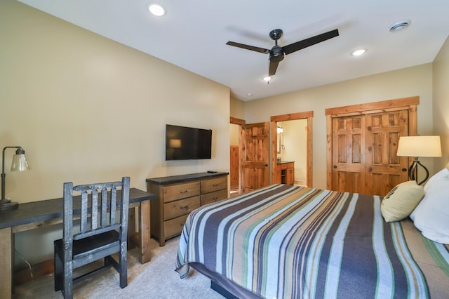 bedroom featuring ceiling fan, light carpet, and ensuite bath