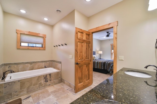 bathroom with ceiling fan, a relaxing tiled tub, and vanity