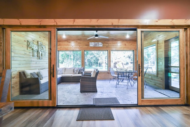 interior space featuring hardwood / wood-style floors, ceiling fan, and wooden walls