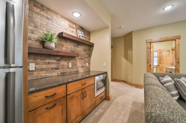 kitchen with a textured ceiling, open shelves, dark stone countertops, appliances with stainless steel finishes, and light colored carpet