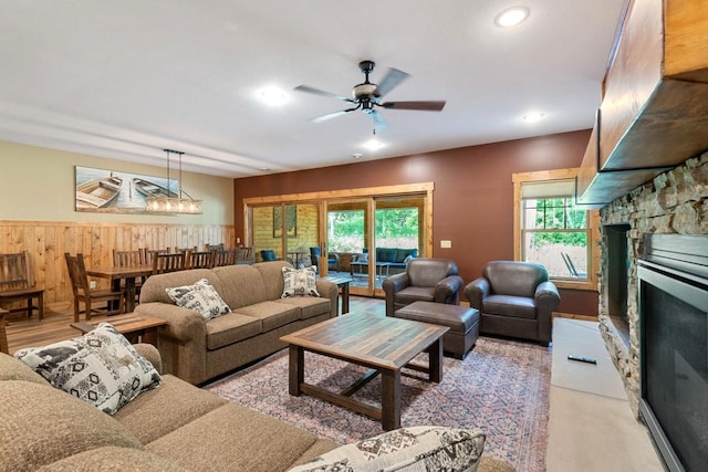 living room featuring ceiling fan and a stone fireplace