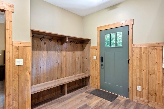 mudroom with hardwood / wood-style flooring and wooden walls