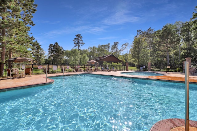 pool with a hot tub, fence, and a patio area