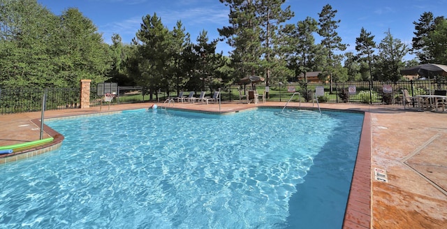 community pool with a patio area and fence