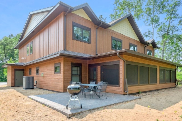 rear view of house with central air condition unit, a patio area, and a sunroom