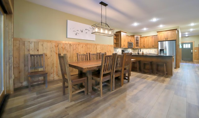 dining space with dark wood-type flooring, sink, and wooden walls