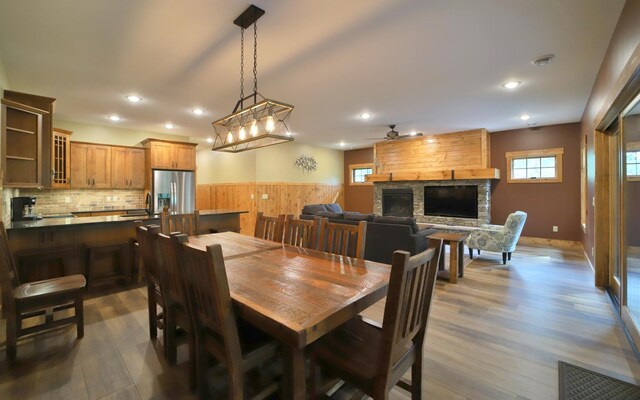 dining room with hardwood / wood-style floors, ceiling fan, sink, and a stone fireplace