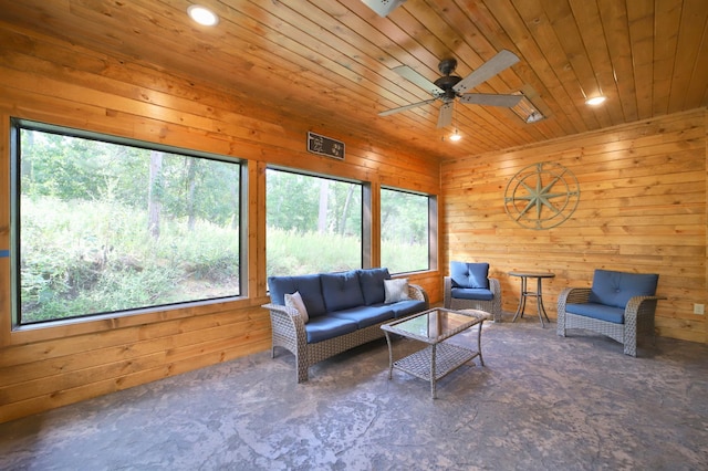 living room with wood walls, ceiling fan, and a healthy amount of sunlight