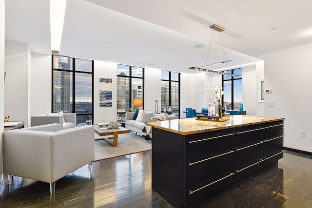 interior space with a center island, light stone counters, a wall of windows, and dark wood-type flooring