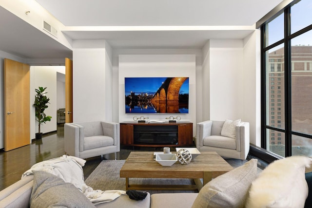 living room with dark wood-type flooring and a wall of windows