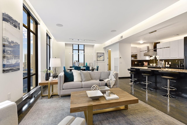 living room featuring dark wood-type flooring, bar area, and a wall of windows