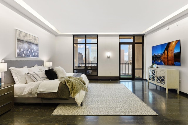 bedroom with dark wood-type flooring, expansive windows, and access to exterior