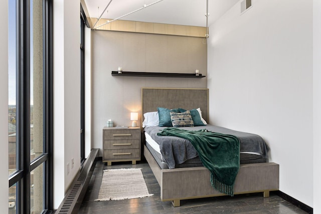 bedroom with a wall of windows, multiple windows, radiator, and dark hardwood / wood-style flooring