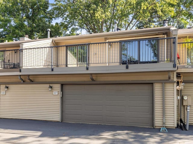 back of property with a balcony and a garage