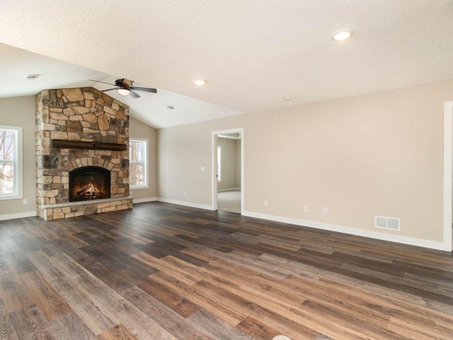 unfurnished living room featuring ceiling fan, lofted ceiling, a textured ceiling, a fireplace, and dark hardwood / wood-style flooring