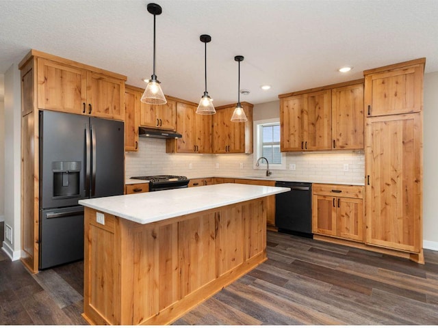 kitchen featuring sink, a kitchen island, decorative light fixtures, dark wood-type flooring, and black appliances