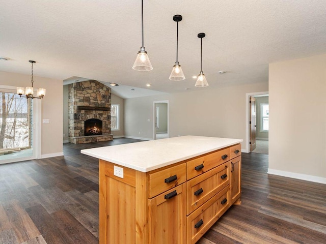 kitchen featuring decorative light fixtures, a fireplace, vaulted ceiling, and a wealth of natural light