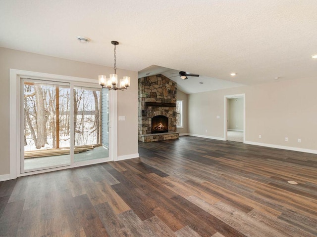 unfurnished living room with ceiling fan with notable chandelier, a fireplace, a textured ceiling, lofted ceiling, and dark hardwood / wood-style floors