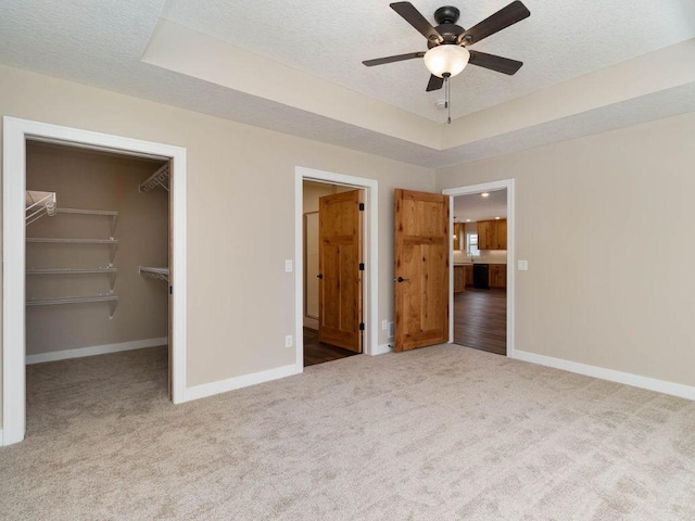 unfurnished bedroom featuring a spacious closet, a closet, a textured ceiling, and ceiling fan