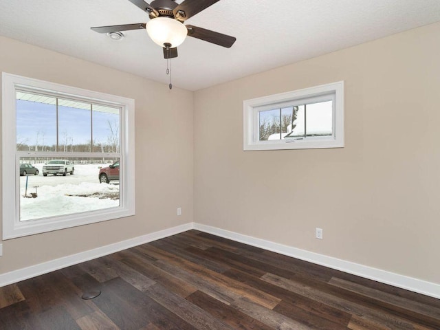 spare room featuring dark wood-type flooring, ceiling fan, and plenty of natural light