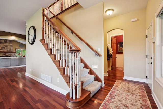 staircase with hardwood / wood-style flooring and a stone fireplace