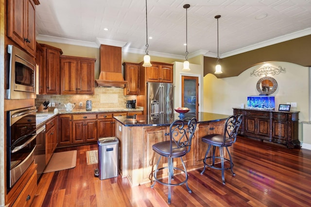 kitchen featuring stainless steel appliances, a kitchen breakfast bar, a kitchen island, decorative light fixtures, and custom exhaust hood