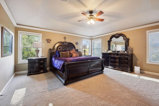 carpeted bedroom with a tray ceiling, ornamental molding, and ceiling fan