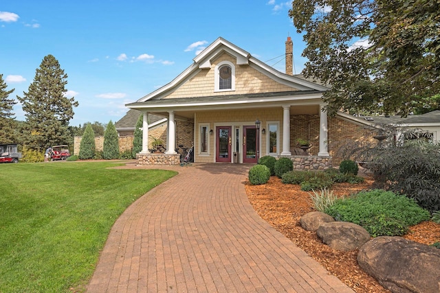 view of front of house with french doors, covered porch, and a front lawn