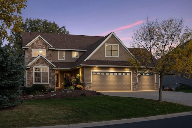 view of front facade with a garage, a lawn, stone siding, and driveway