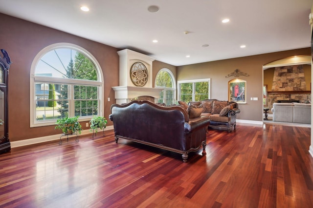 living room featuring a stone fireplace, recessed lighting, and wood finished floors