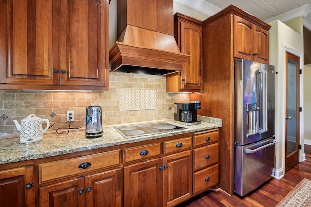 kitchen with dark wood-type flooring, custom range hood, black electric cooktop, light stone countertops, and high end refrigerator