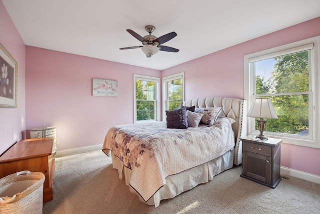 bedroom featuring baseboards, multiple windows, light carpet, and a ceiling fan