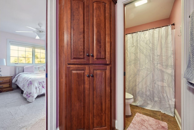 bathroom with toilet, a ceiling fan, curtained shower, tile patterned flooring, and baseboards