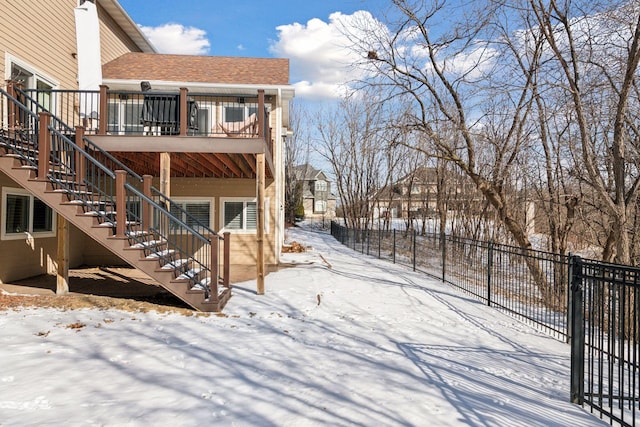 snowy yard with stairway, a deck, and fence