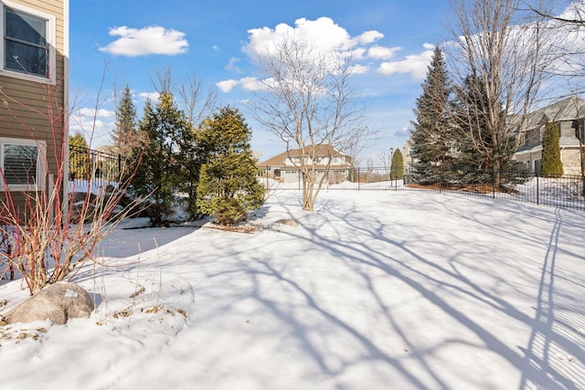 yard covered in snow featuring fence