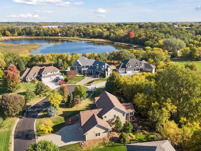 drone / aerial view featuring a residential view, a wooded view, and a water view