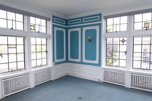 unfurnished sunroom featuring radiator heating unit and plenty of natural light