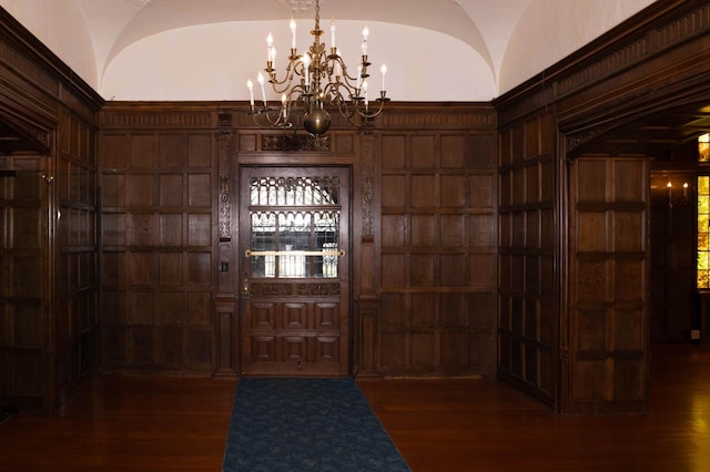 foyer featuring a notable chandelier, wooden walls, and dark hardwood / wood-style flooring