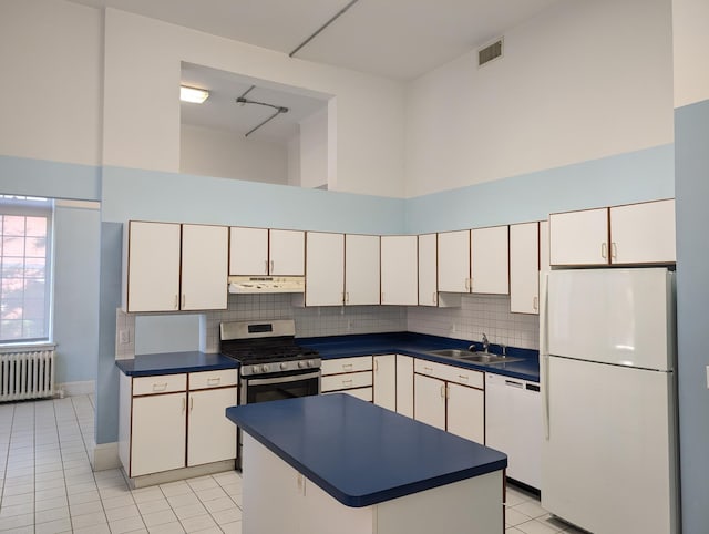 kitchen with white appliances, a towering ceiling, radiator heating unit, and white cabinets