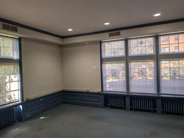 unfurnished room featuring radiator heating unit, carpet flooring, and crown molding