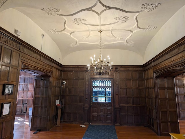 foyer entrance with an inviting chandelier, dark hardwood / wood-style floors, and vaulted ceiling