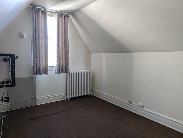 bonus room with a healthy amount of sunlight, lofted ceiling, dark colored carpet, and radiator heating unit