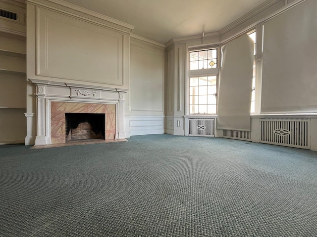 unfurnished living room featuring a fireplace, crown molding, and carpet flooring