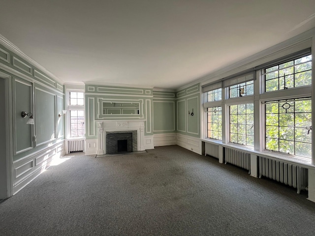 unfurnished living room featuring radiator heating unit, a wealth of natural light, and a premium fireplace