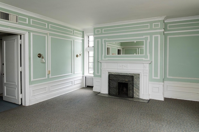 unfurnished living room featuring radiator heating unit, a fireplace, ornamental molding, and carpet