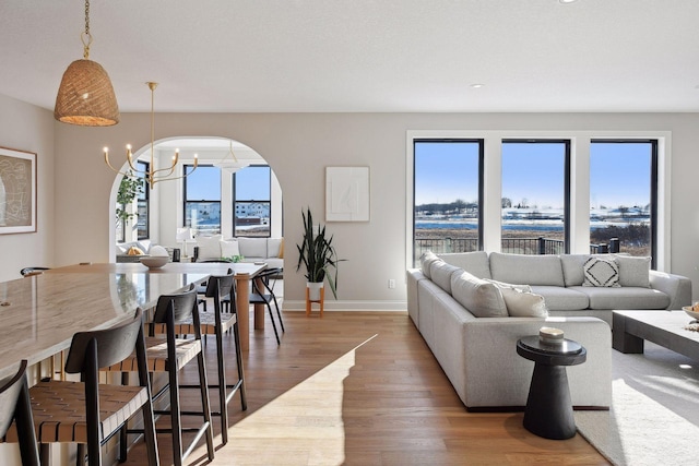 living room featuring a notable chandelier, light hardwood / wood-style floors, and plenty of natural light