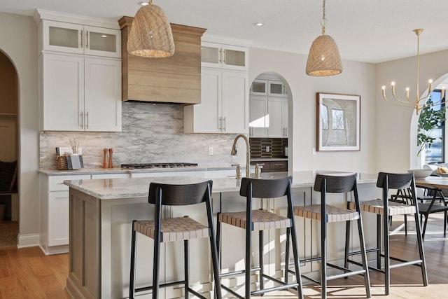 kitchen featuring a kitchen island with sink, a breakfast bar, and white cabinetry