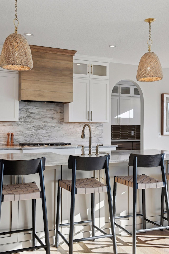 kitchen with decorative backsplash, decorative light fixtures, white cabinetry, and a breakfast bar area