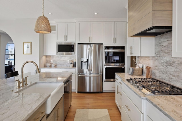 kitchen with stainless steel appliances, white cabinetry, pendant lighting, and premium range hood